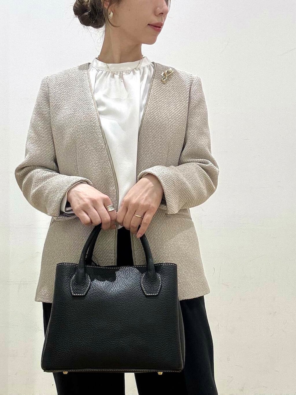 ブラック系のショルダーバッグ、ベージュ系のベスト、グレー系のスーツジャケットを着用したレディースの春コーディネートの7枚目の写真