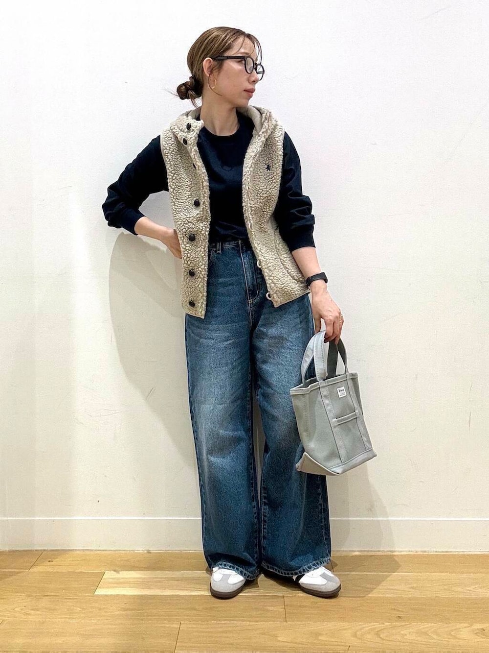 ブルー系のデニムパンツ、ホワイト系のスニーカー、グレー系のトートバッグを着用したレディースの秋コーディネートの2枚目の写真