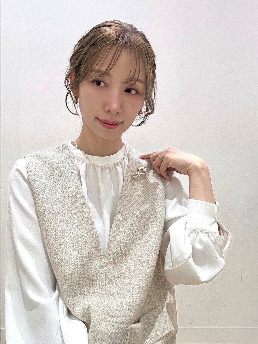 ブラック系のショルダーバッグ、ベージュ系のベスト、グレー系のスーツジャケットを着用したレディースの春コーディネートの8枚目の写真