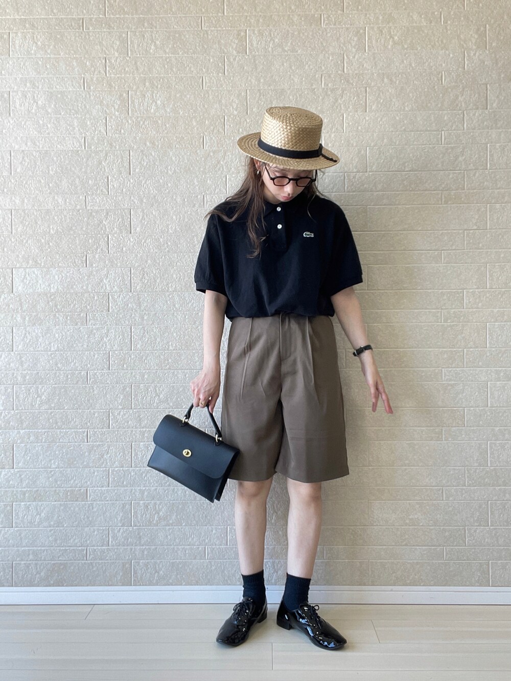 ブラック系のポロシャツ、ブラウン系のその他パンツ、ブラック系のドレスシューズを着用したレディースの夏コーディネートの3枚目の写真