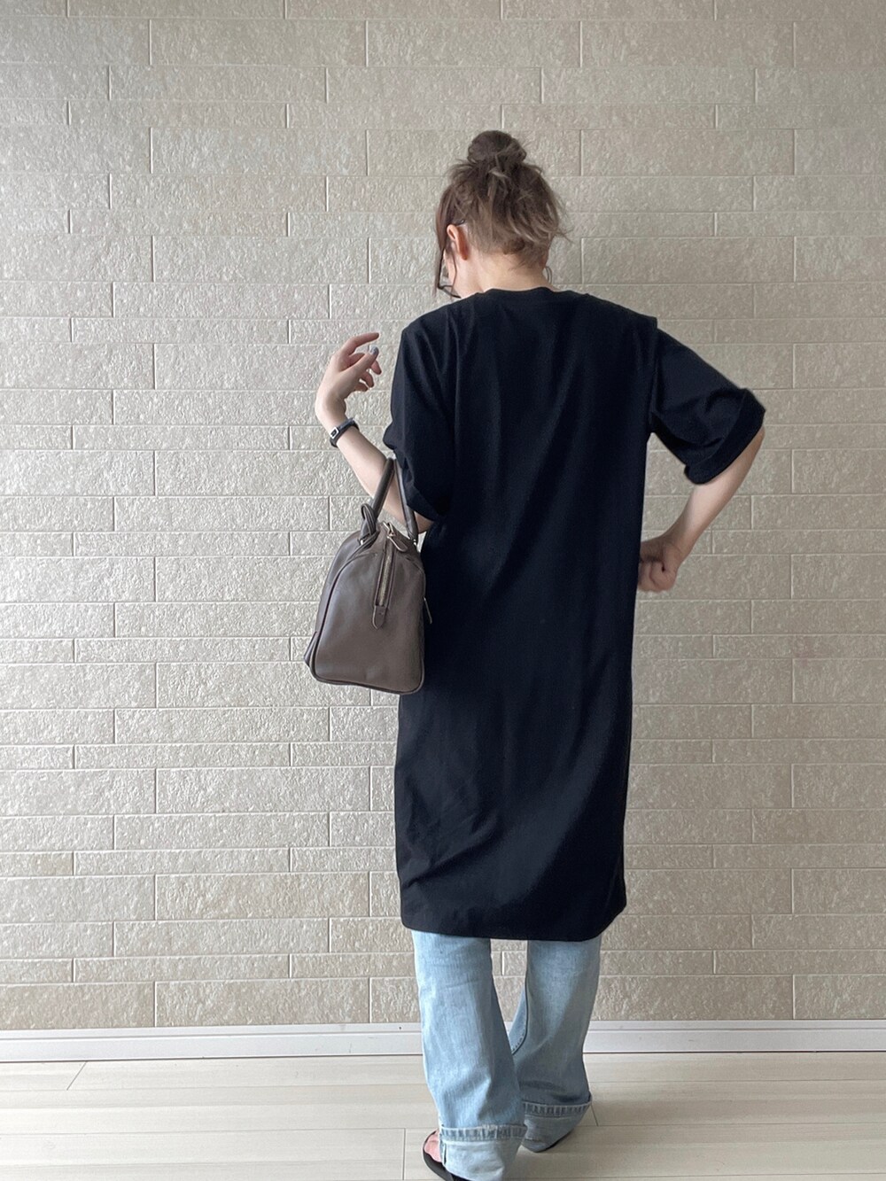 ブラック系のワンピース、ブラウン系のボストンバッグ、ブルー系のデニムパンツを着用したレディースの夏コーディネートの3枚目の写真