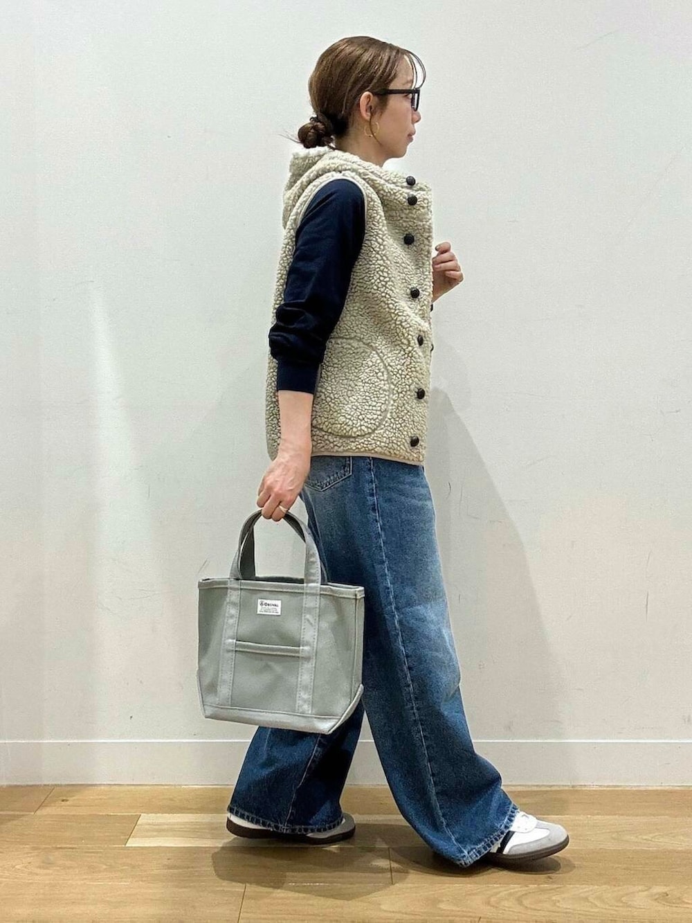 ブルー系のデニムパンツ、ホワイト系のスニーカー、グレー系のトートバッグを着用したレディースの秋コーディネートの3枚目の写真