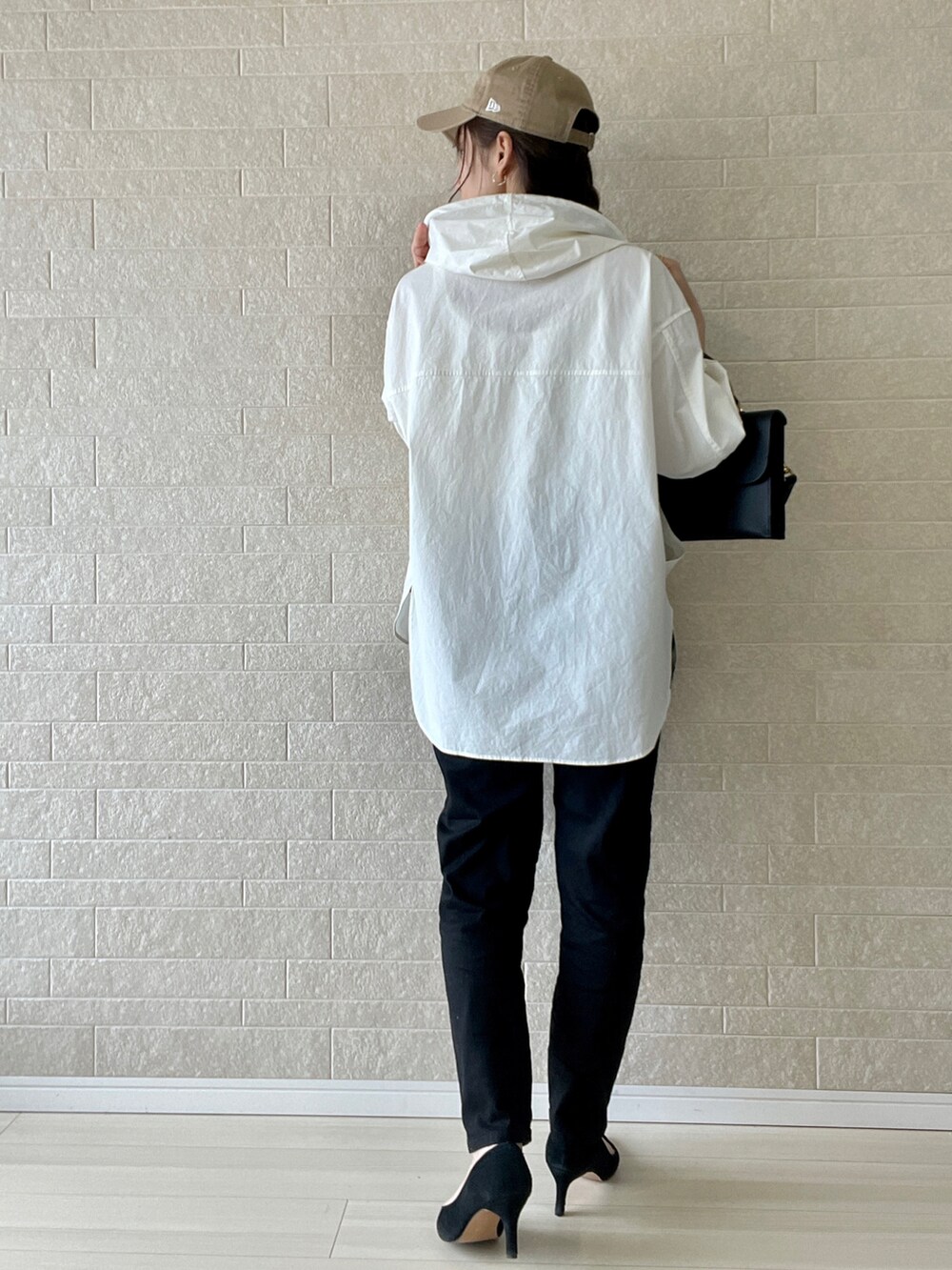 ブラック系のデニムパンツ、ホワイト系のマウンテンパーカー、ブラック系のショルダーバッグを着用したレディースの春コーディネートの4枚目の写真