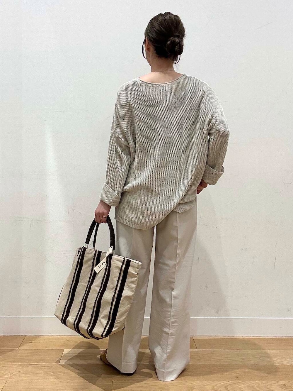 ベージュ系のニット/セーター、イエロー系のサンダル、ブラウン系のトートバッグを着用したレディースの春コーディネートの6枚目の写真