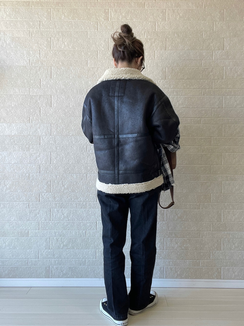 ブラック系のムートンコート、ブラック系のデニムパンツ、ブラウン系のショルダーバッグを着用したレディースの秋コーディネートの4枚目の写真