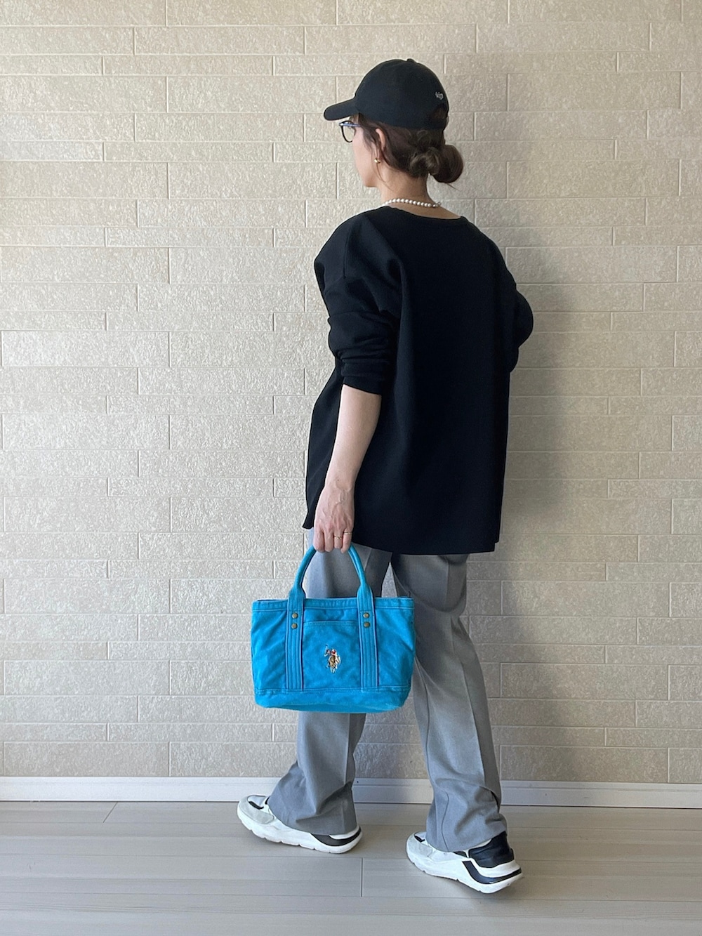 ブルー系のトートバッグ、グレー系のスラックス、ホワイト系のスニーカーを着用したレディースの冬コーディネートの3枚目の写真