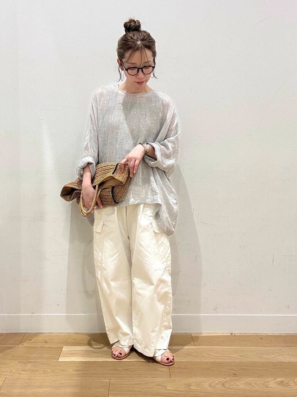 ベージュ系のトートバッグ、ホワイト系のサンダル、ベージュ系のタンクトップを着用したレディースの春コーディネートの6枚目の写真