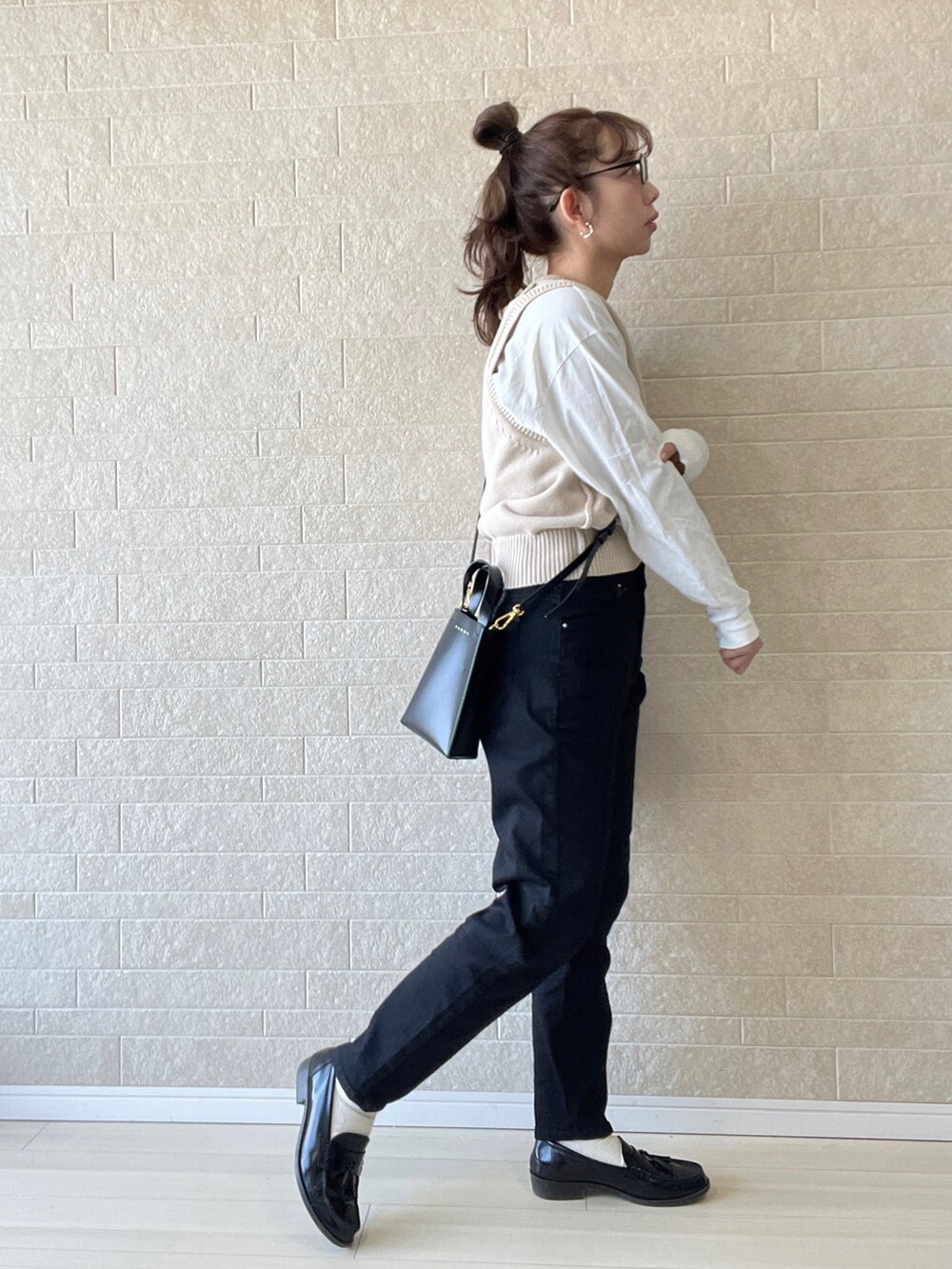 ブラック系のデニムパンツ、ベージュ系のベスト、ホワイト系のTシャツ/カットソーを着用したレディースの春コーディネートの3枚目の写真