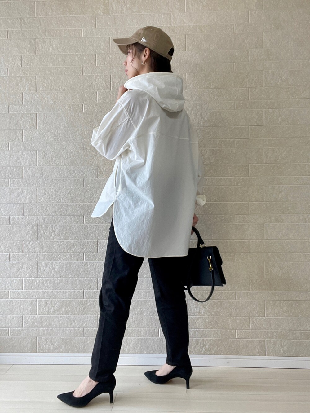 ブラック系のデニムパンツ、ホワイト系のマウンテンパーカー、ブラック系のショルダーバッグを着用したレディースの春コーディネートの5枚目の写真