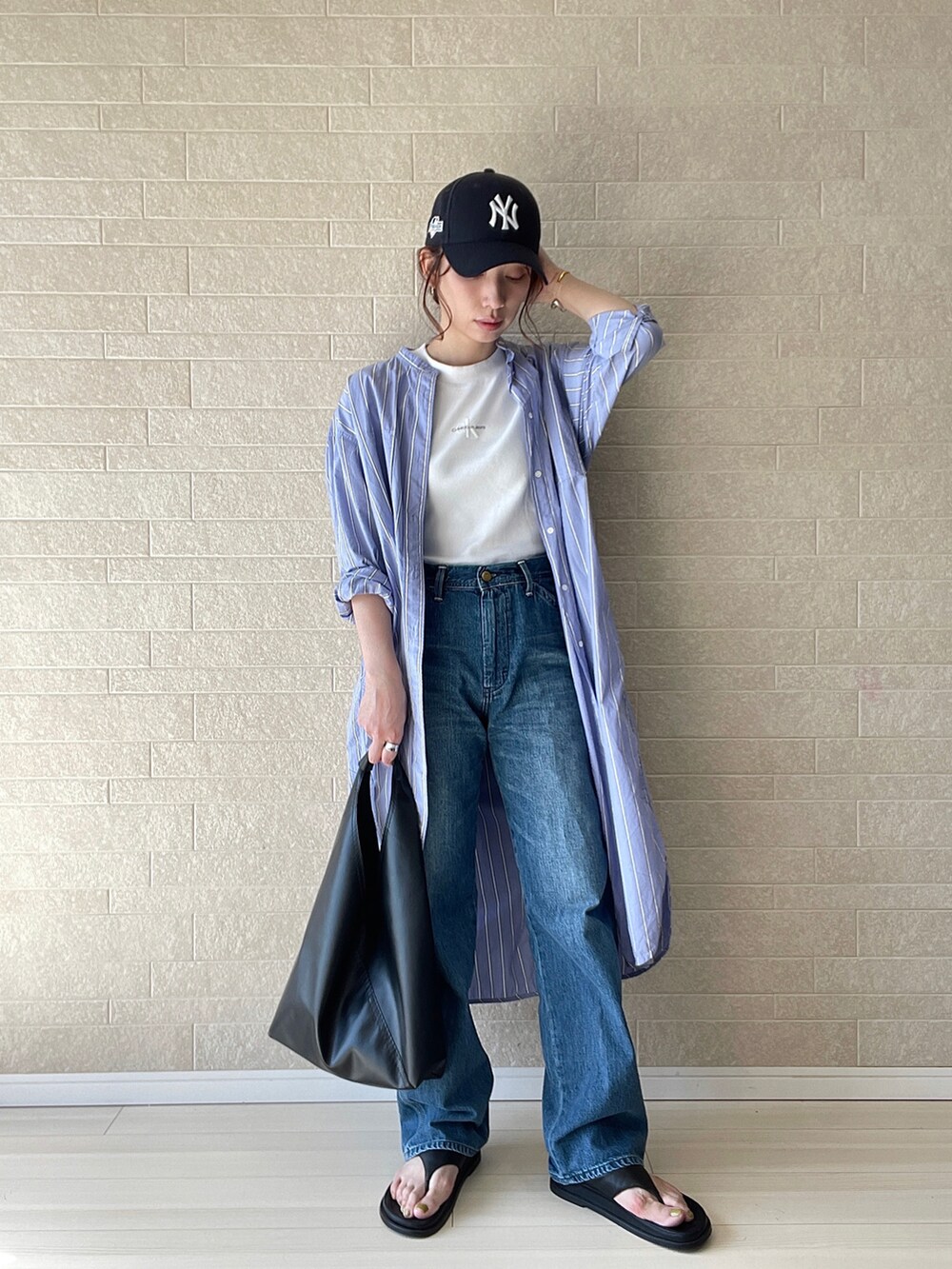 ブルー系のデニムパンツ、ホワイト系のTシャツ/カットソー、ブラック系のトートバッグを着用したレディースの春コーディネートの5枚目の写真