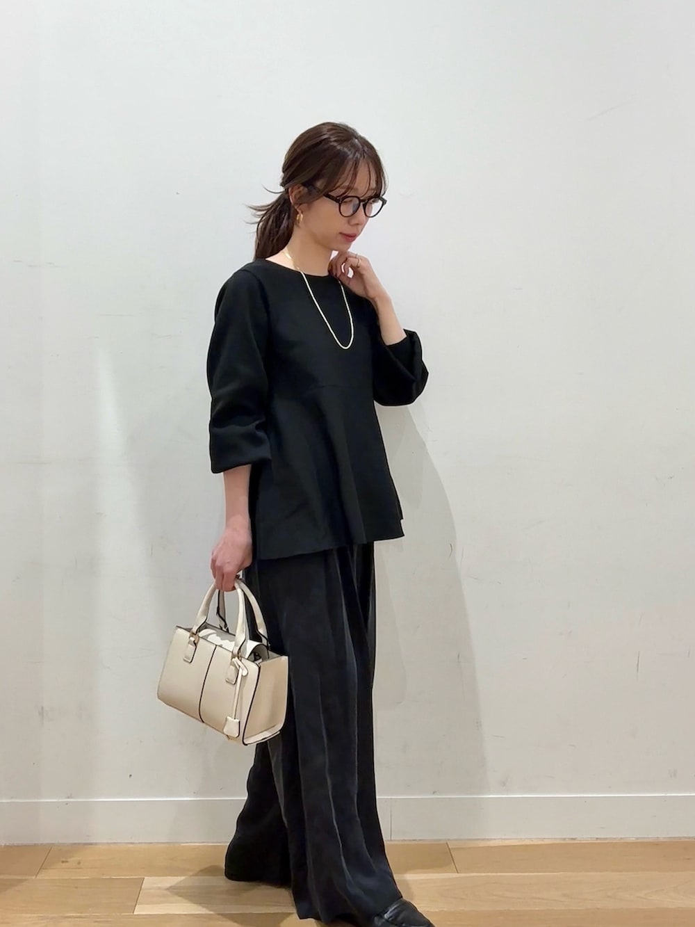 ホワイト系のハンドバッグ、ブラウン系のその他アウター、ブラック系のニット/セーターを着用したレディースの冬コーディネートの6枚目の写真