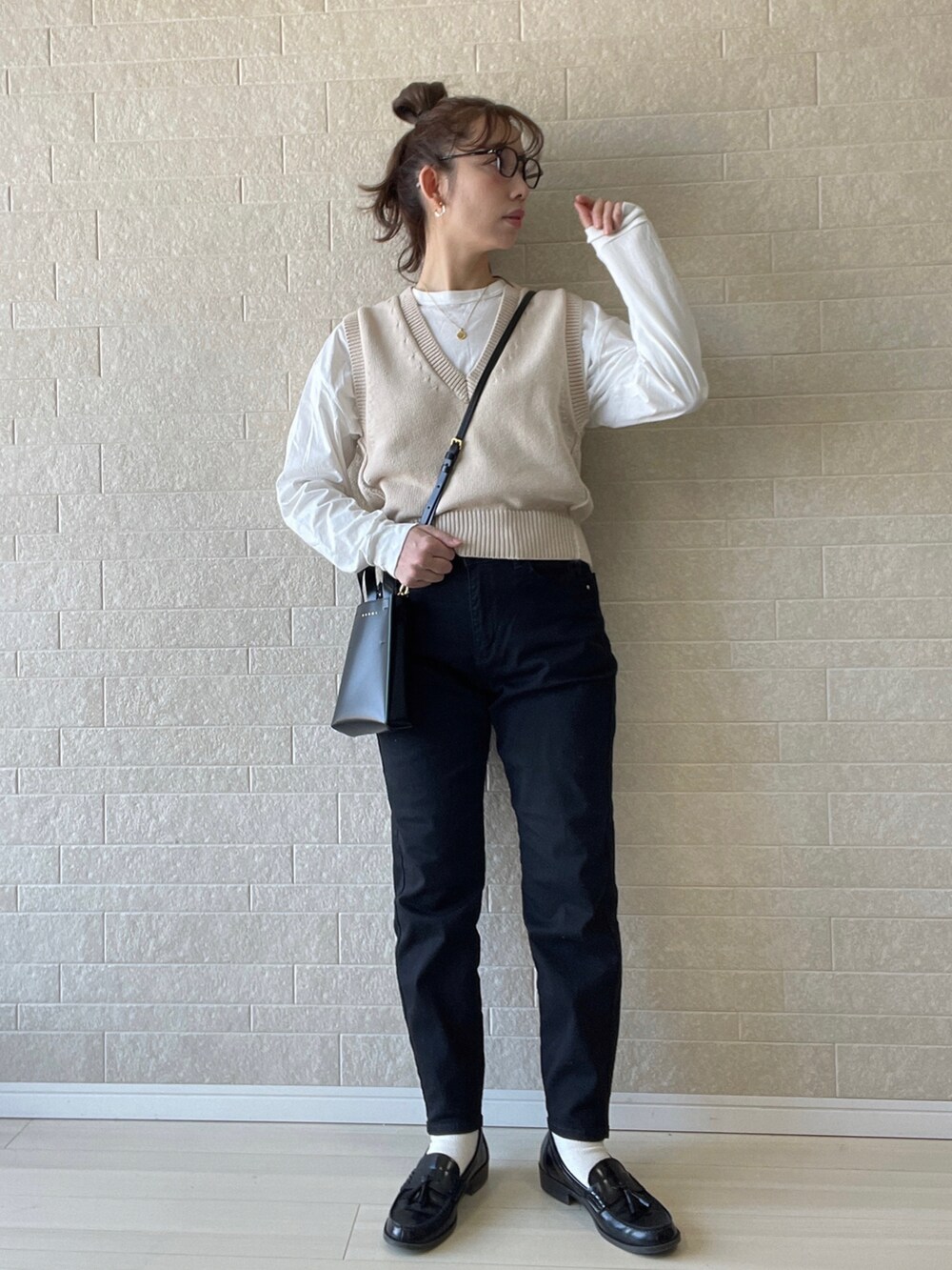 ブラック系のデニムパンツ、ベージュ系のベスト、ホワイト系のTシャツ/カットソーを着用したレディースの春コーディネートの2枚目の写真