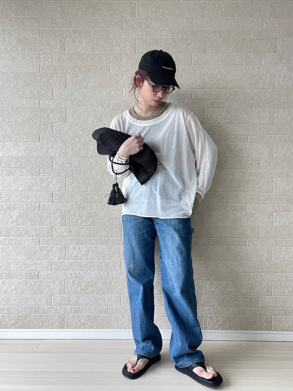 ブルー系のデニムパンツ、ホワイト系のTシャツ/カットソー、ブラック系のサンダルを着用したレディースの春コーディネートの2枚目の写真