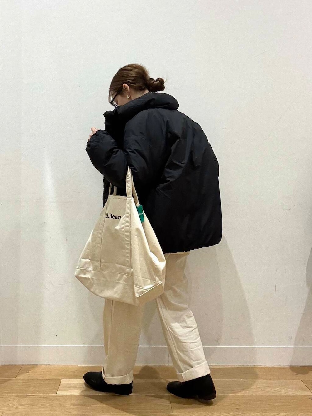 ホワイト系のトートバッグ、ベージュ系のデニムパンツ、ブラック系のブーツを着用したレディースの冬コーディネートの3枚目の写真