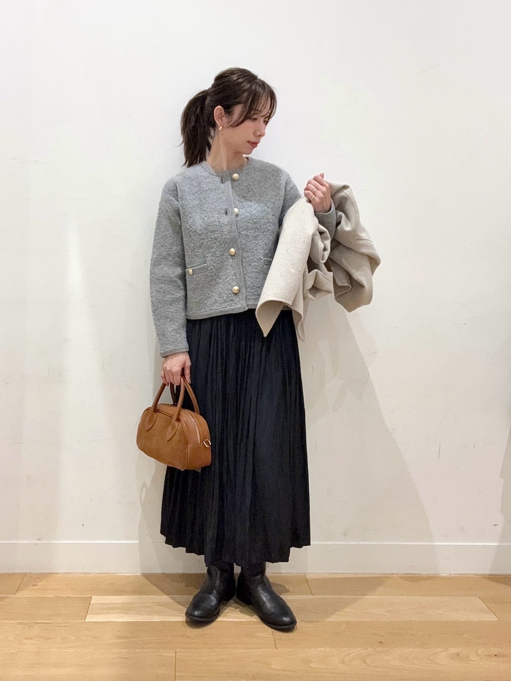 ブラウン系のショルダーバッグ、ブラック系のブーツ、ブラック系のスカートを着用したレディースの秋コーディネートの4枚目の写真