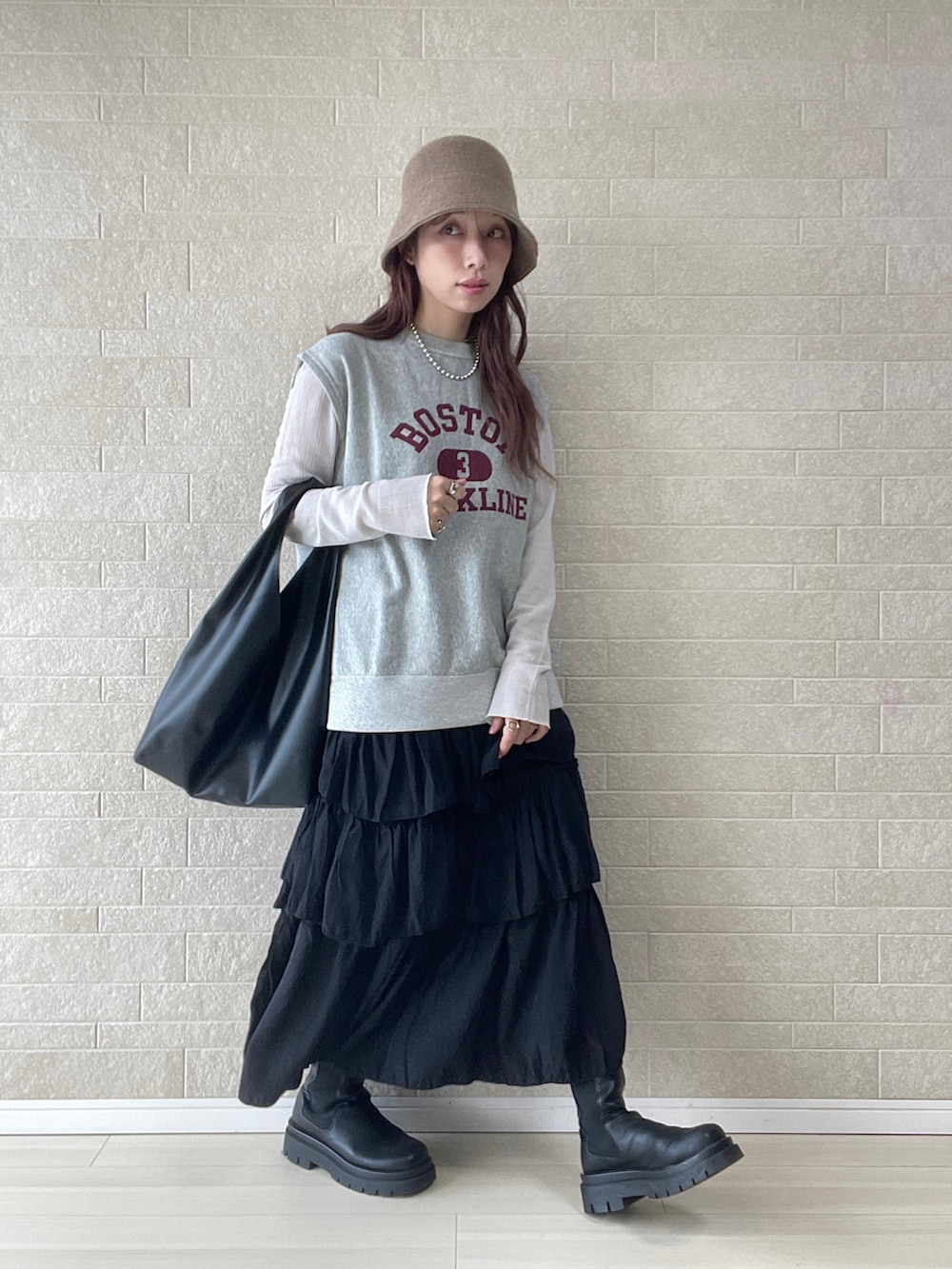 ブラック系のスカート、ブラック系のトートバッグ、グレー系のベストを着用したレディースの春コーディネートの4枚目の写真