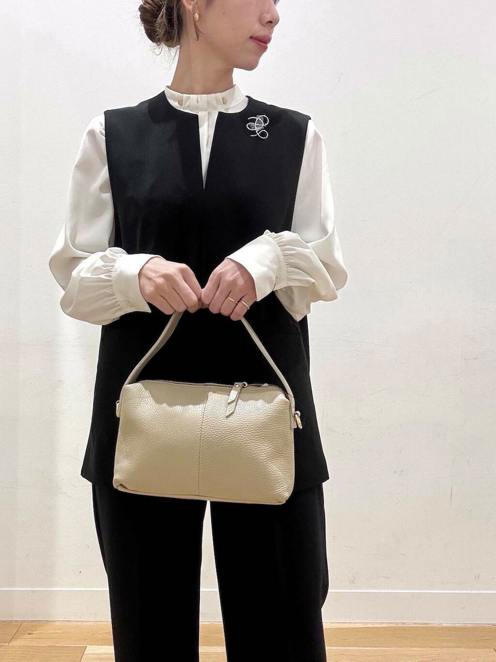 ホワイト系のショルダーバッグ、ブラック系のベスト、ホワイト系のシャツ/ブラウスを着用したレディースの冬コーディネートの5枚目の写真