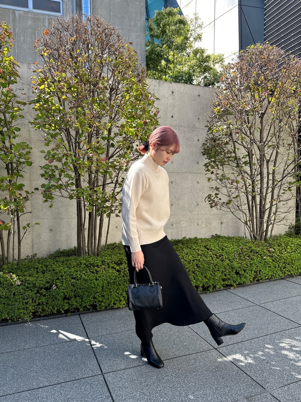 ホワイト系のニット/セーター、ブラック系のスカート、ブラック系のショルダーバッグを着用したレディースの秋コーディネートの4枚目の写真