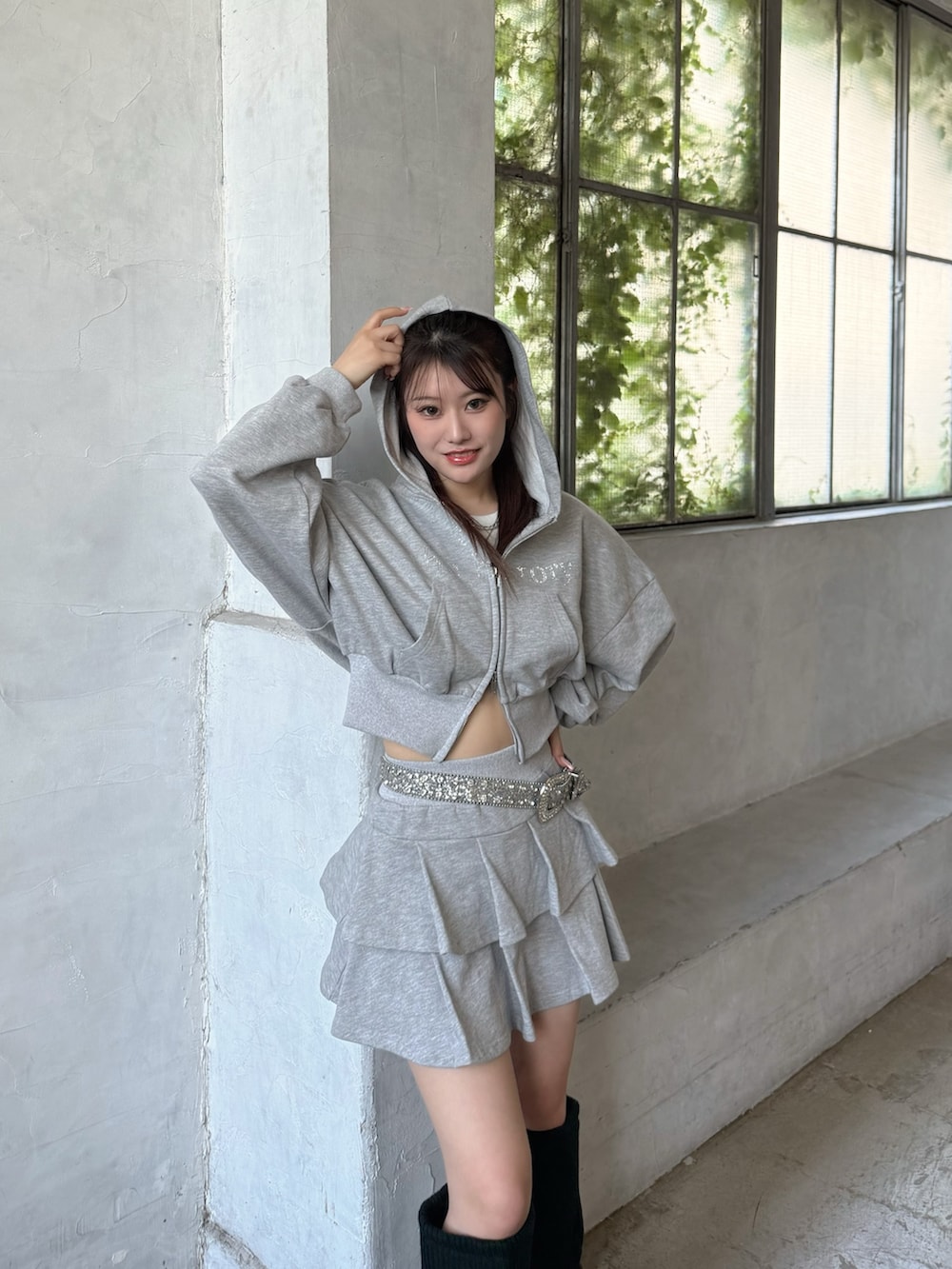 グレー系のパーカー、グレー系のスカート、ブラック系のブーツを着用したレディースの夏コーディネートの2枚目の写真