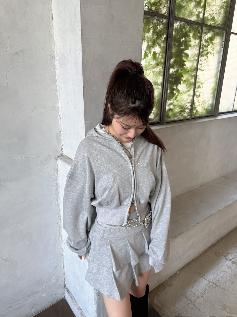 グレー系のパーカー、グレー系のスカート、ブラック系のブーツを着用したレディースの夏コーディネートの4枚目の写真
