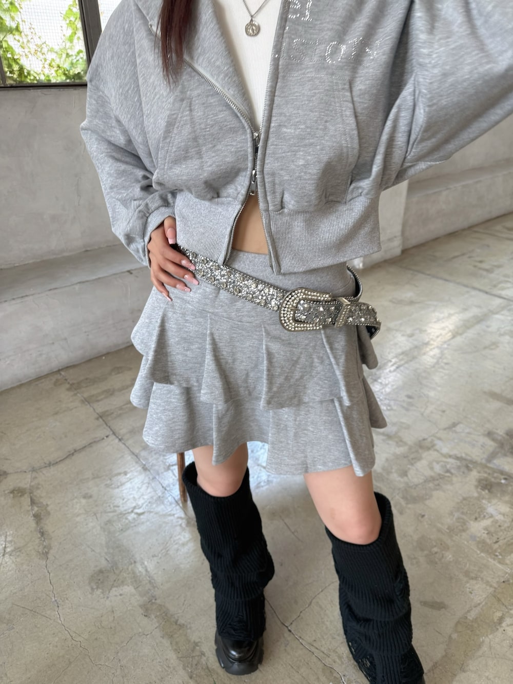 グレー系のパーカー、グレー系のスカート、ブラック系のブーツを着用したレディースの夏コーディネートの5枚目の写真