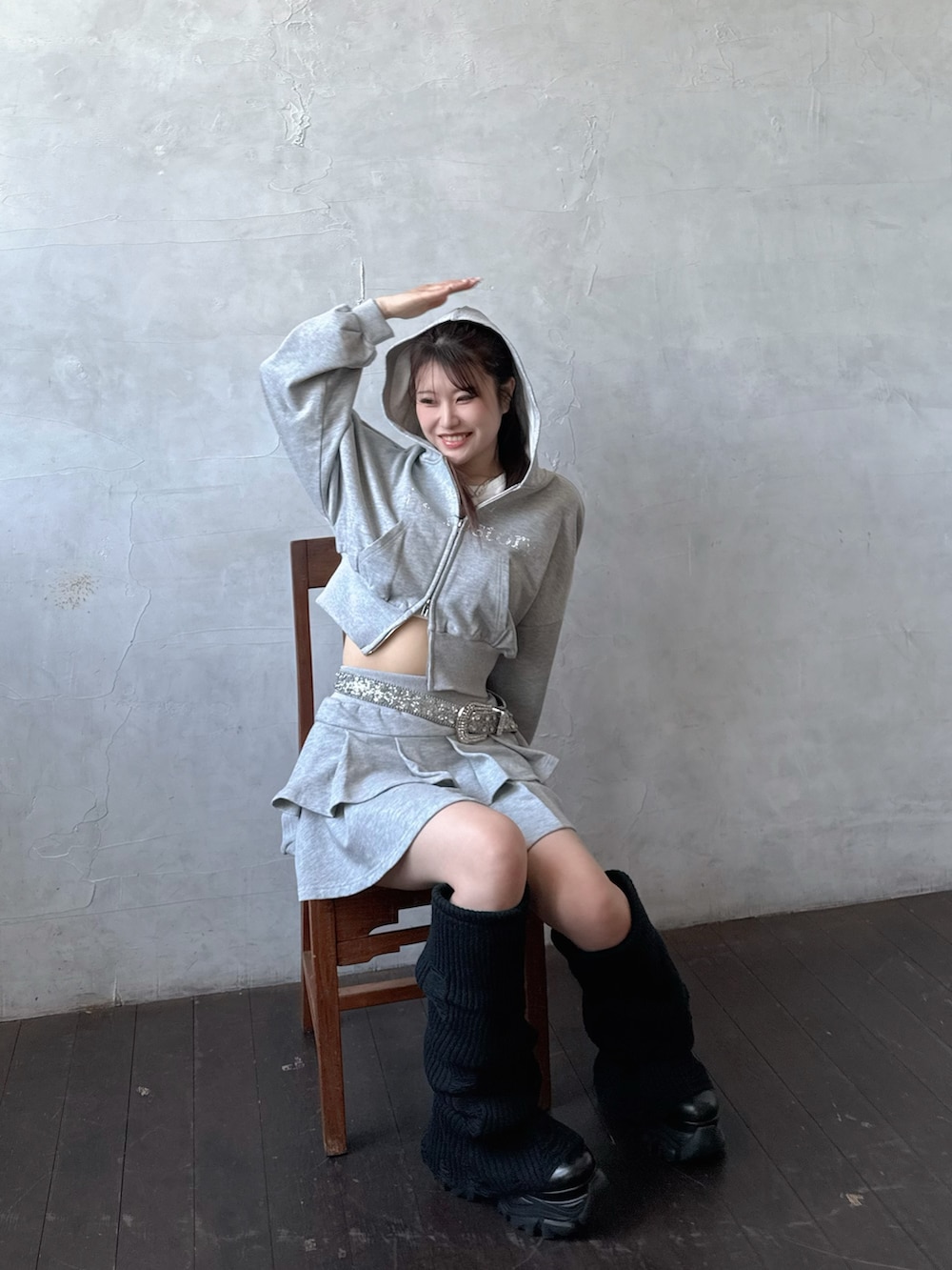 グレー系のパーカー、グレー系のスカート、ブラック系のブーツを着用したレディースの夏コーディネートの3枚目の写真