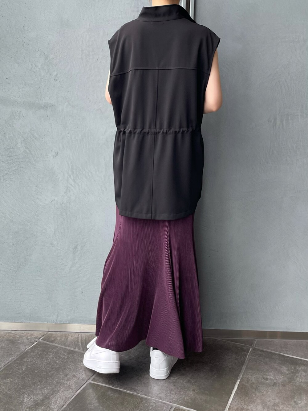 ブラック系のベスト、パープル系のスカートを着用したレディースの夏コーディネートの2枚目の写真