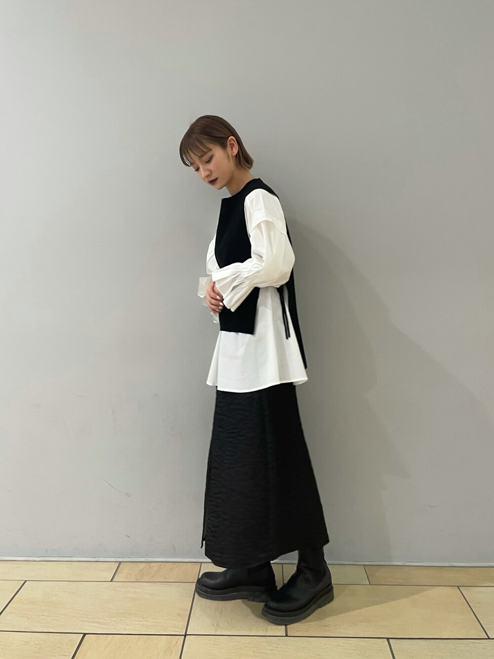 ブラック系のスカート、ブラック系のベストを着用したレディースの冬コーディネートの2枚目の写真