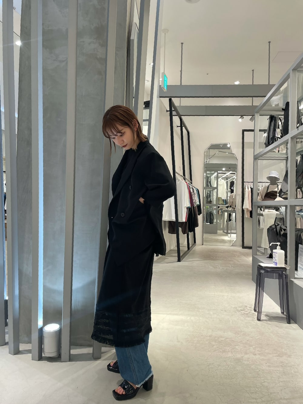 ブラック系のテーラードジャケット、ブラック系のワンピース、ブルー系のデニムパンツを着用したレディースの春コーディネートの2枚目の写真