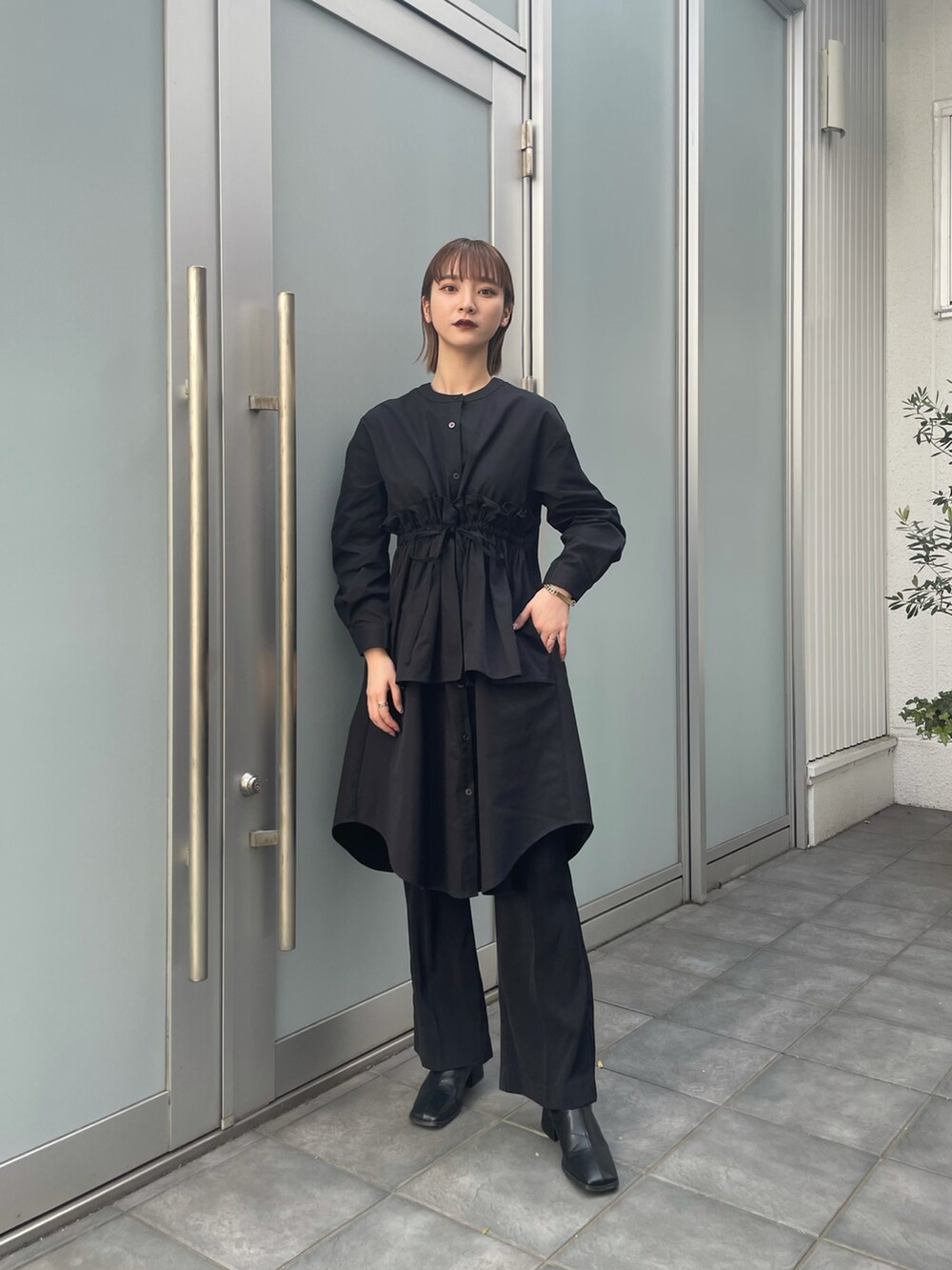 ブラック系のブーツ、ブラック系のワンピース、ブラック系のスラックスを着用したレディースの春コーディネートの2枚目の写真