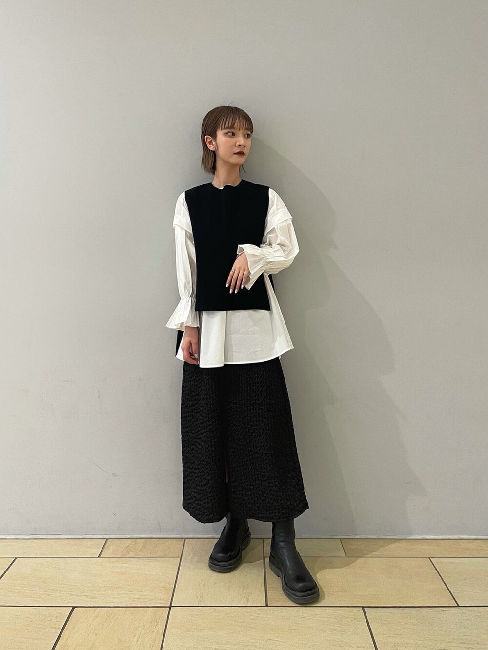 ブラック系のスカート、ブラック系のベスト、ブラック系のブーツを着用したレディースの冬コーディネートの3枚目の写真