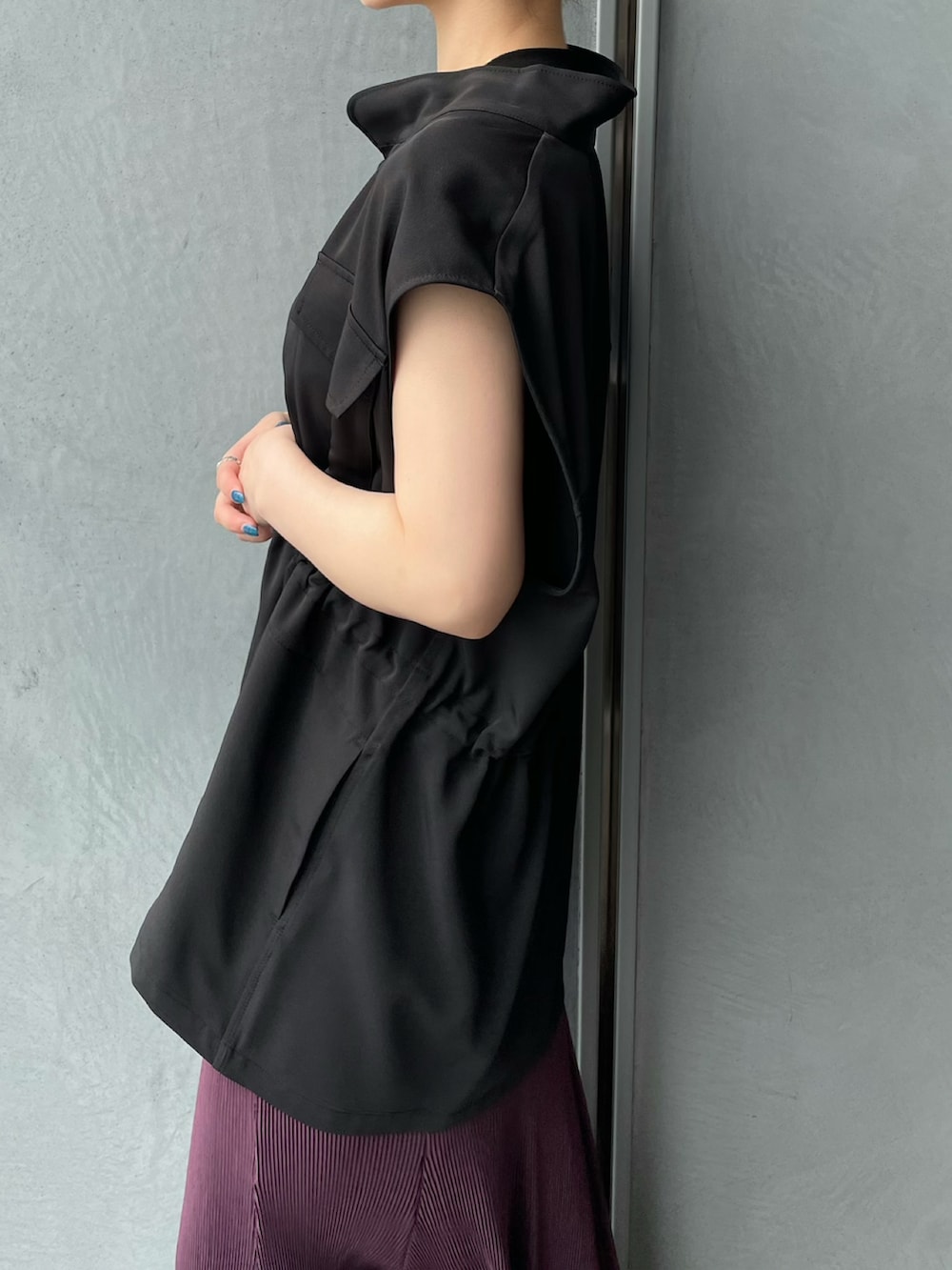 ブラック系のベスト、パープル系のスカートを着用したレディースの夏コーディネートの3枚目の写真