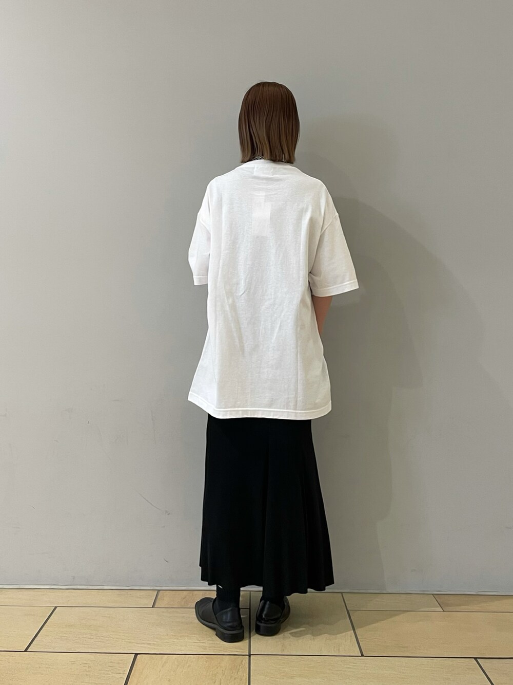 ホワイト系のTシャツ/カットソー、ブラック系のスカート、ブラック系のパンプスを着用したレディースの春コーディネートの2枚目の写真