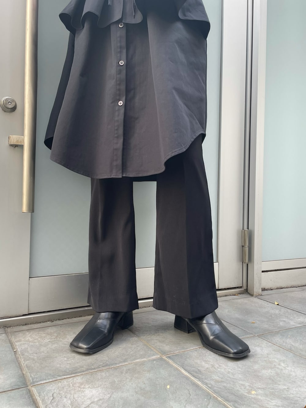 ブラック系のブーツ、ブラック系のワンピース、ブラック系のスラックスを着用したレディースの春コーディネートの3枚目の写真