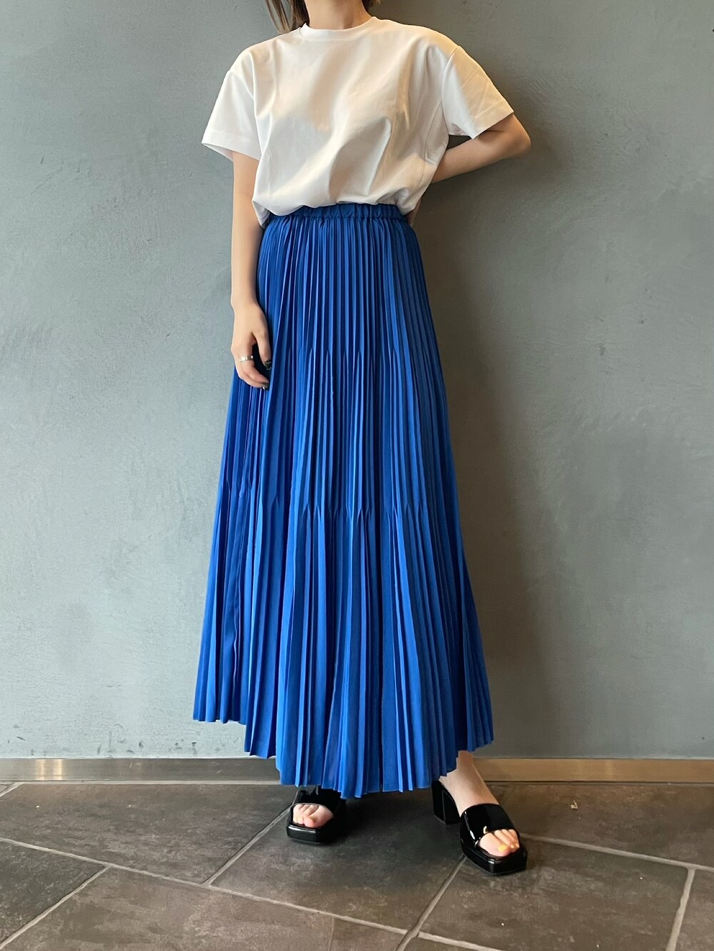 ブルー系のスカート、ホワイト系のTシャツ/カットソーを着用したレディースの夏コーディネートの2枚目の写真