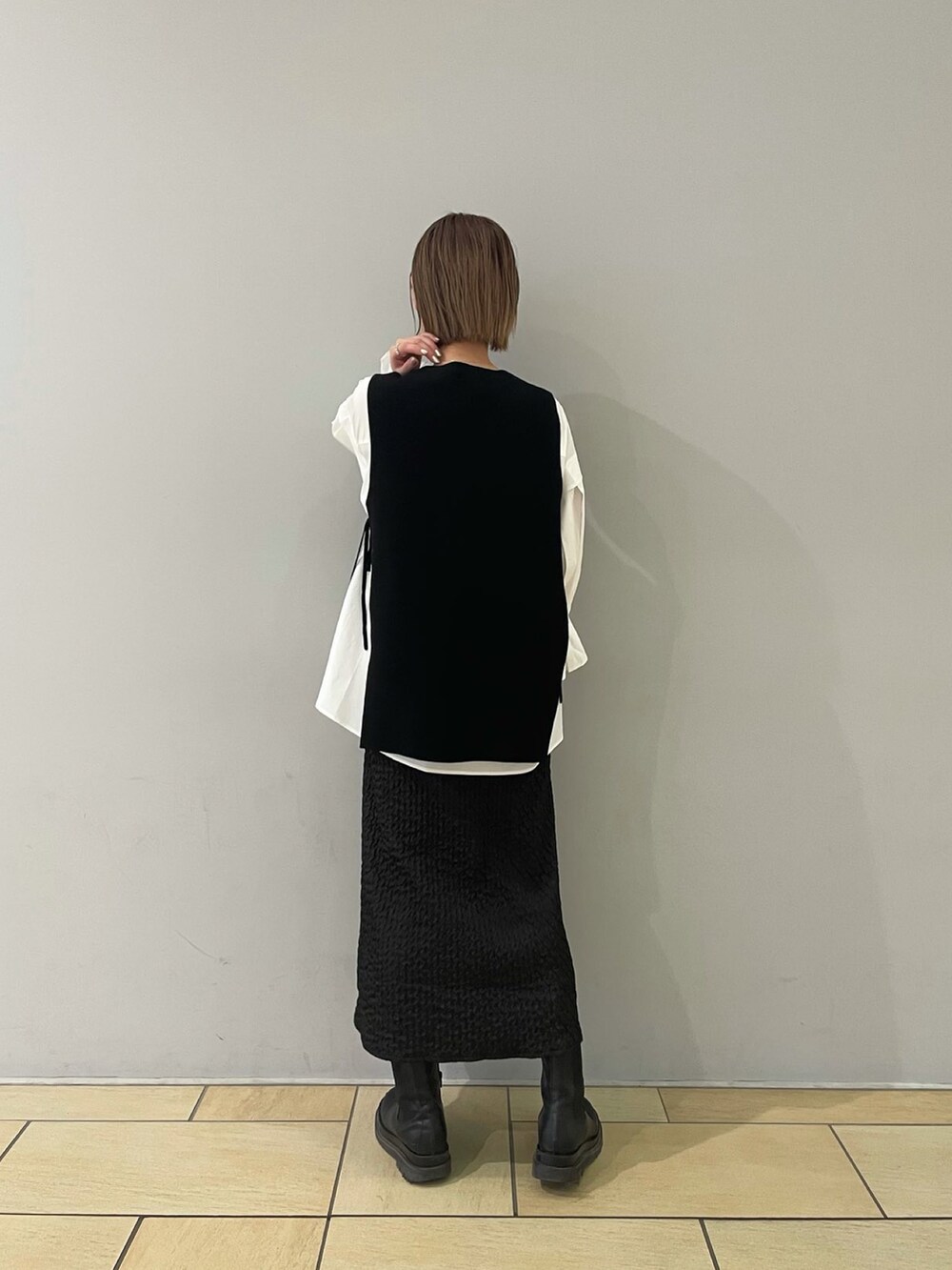 ブラック系のスカート、ブラック系のベスト、ブラック系のブーツを着用したレディースの冬コーディネートの4枚目の写真