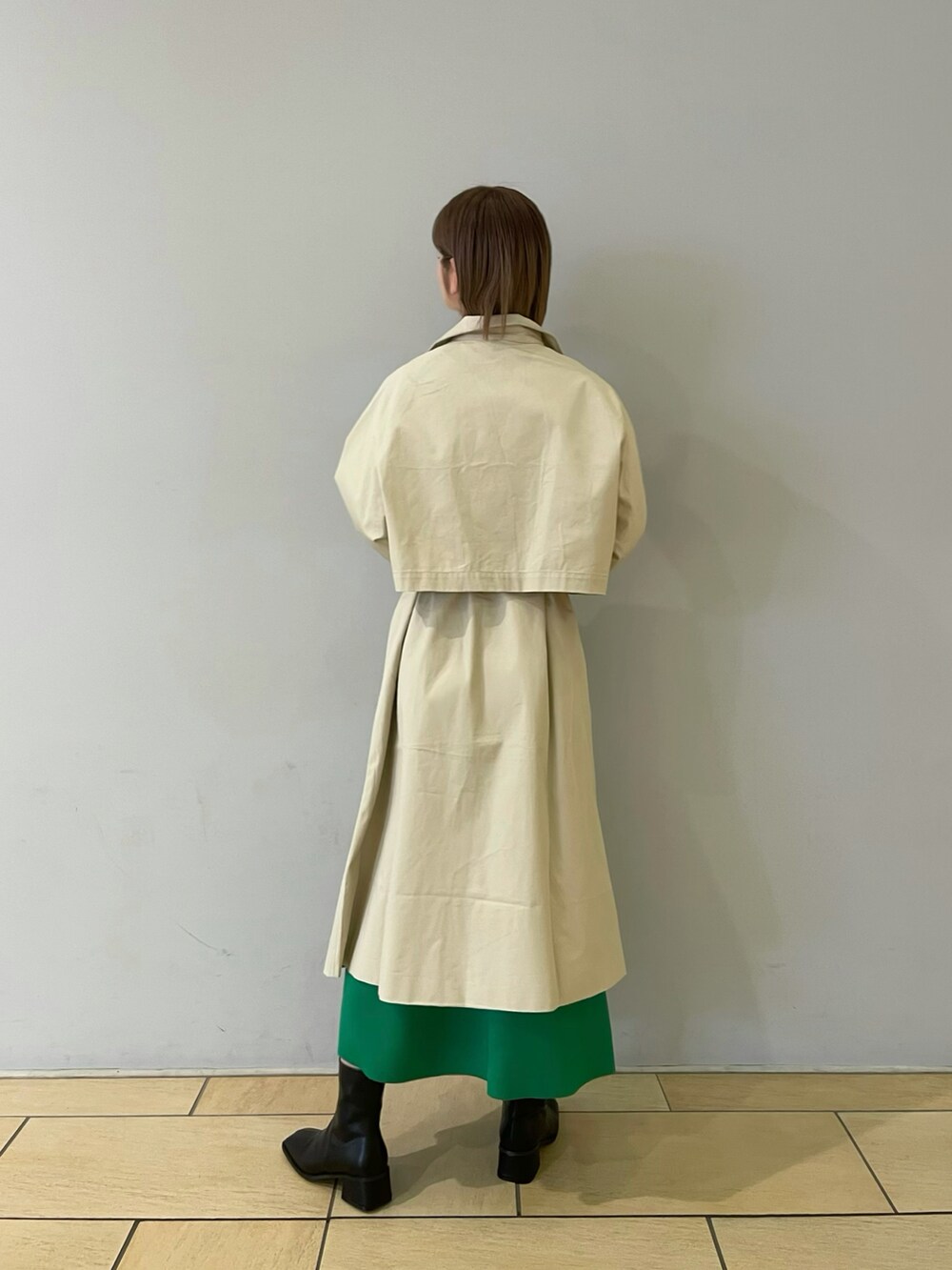 ベージュ系のトレンチコート、グリーン系のスカート、ブラック系のブーツを着用したレディースの冬コーディネートの3枚目の写真