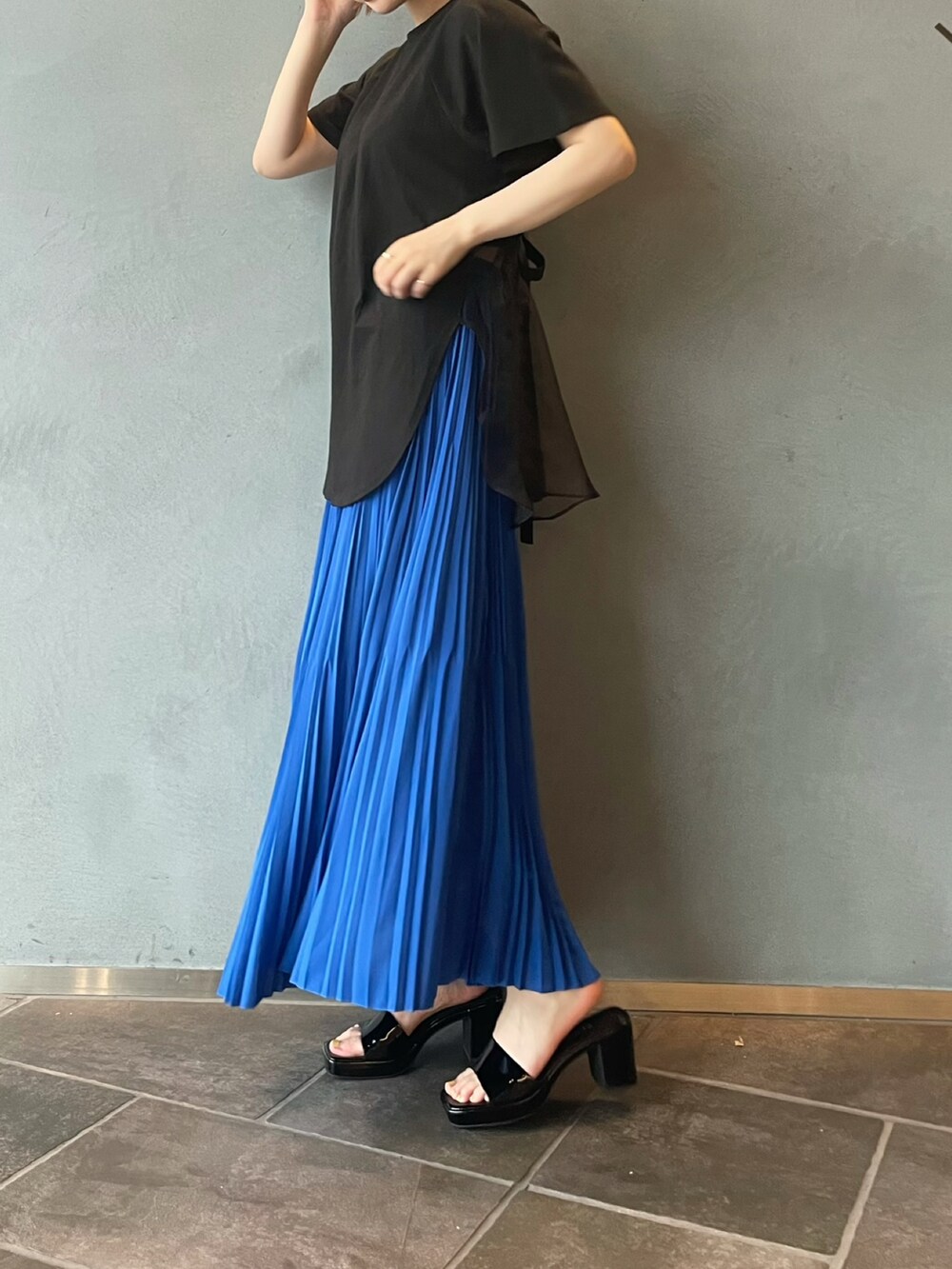 ブルー系のスカート、ブラック系のTシャツ/カットソーを着用したレディースの夏コーディネートの2枚目の写真