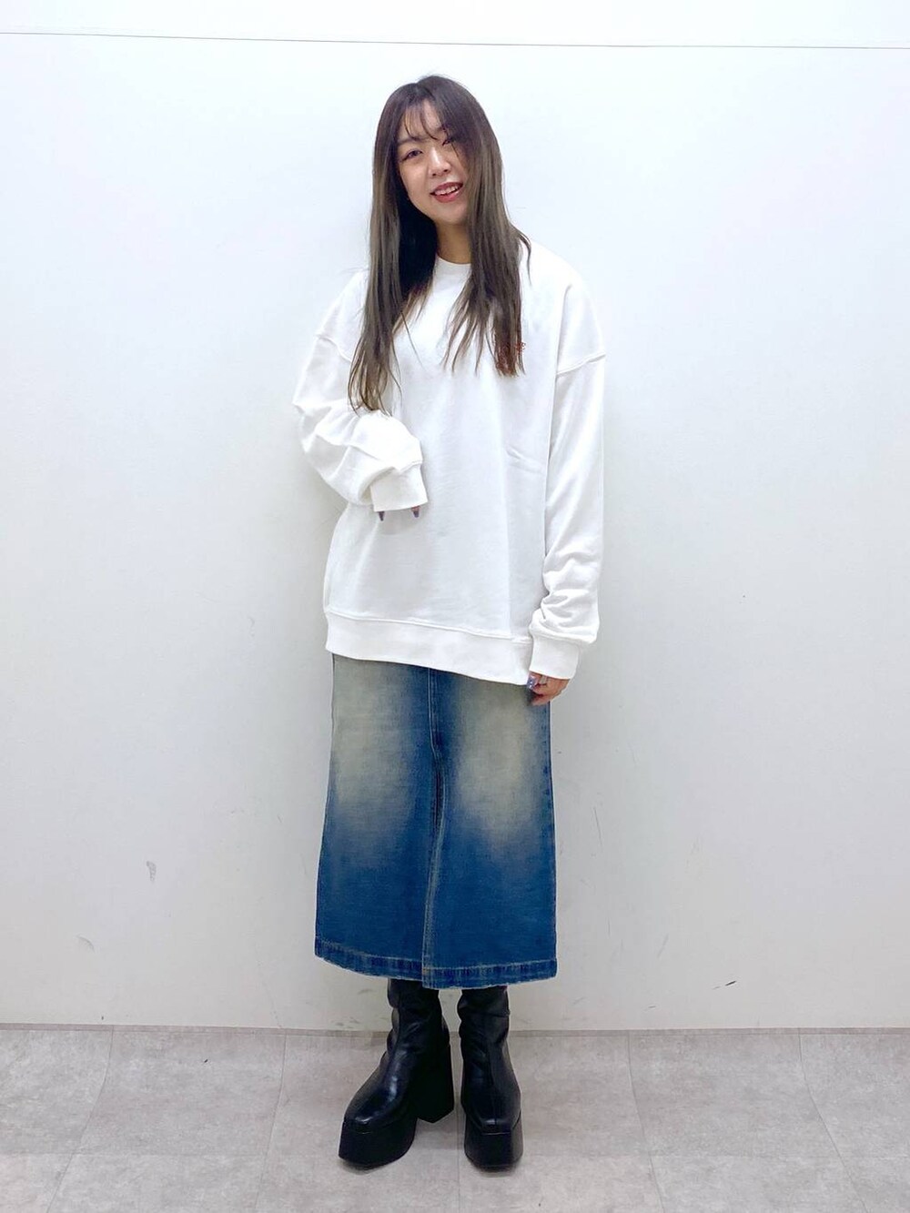 ブラック系のブーツ、ホワイト系のスウェット、ブルー系のスカートを着用したレディースの秋コーディネートの2枚目の写真