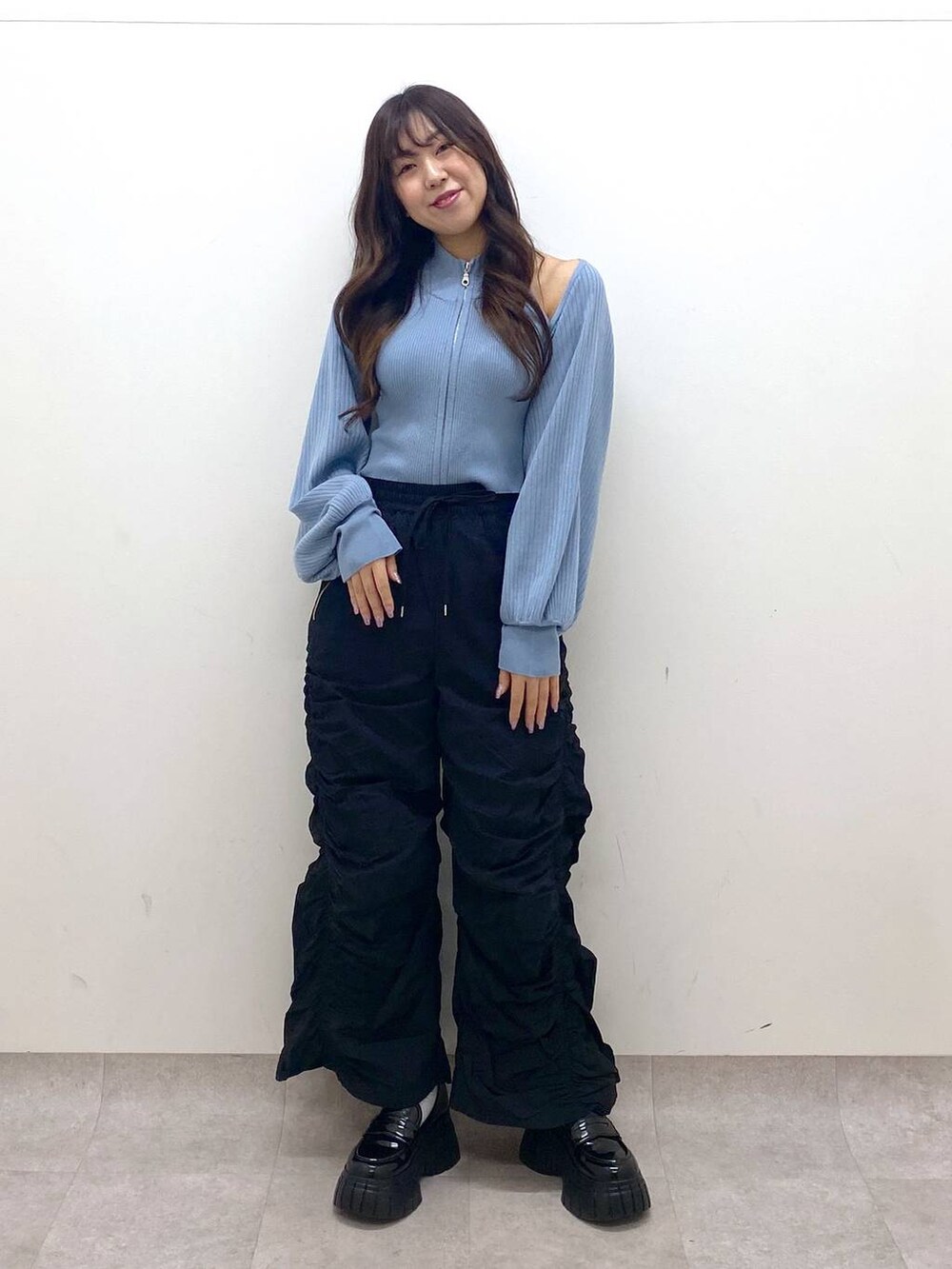 ブラック系のその他パンツ、ブラック系のローファー、ブルー系のニット/セーターを着用したレディースの冬コーディネートの2枚目の写真