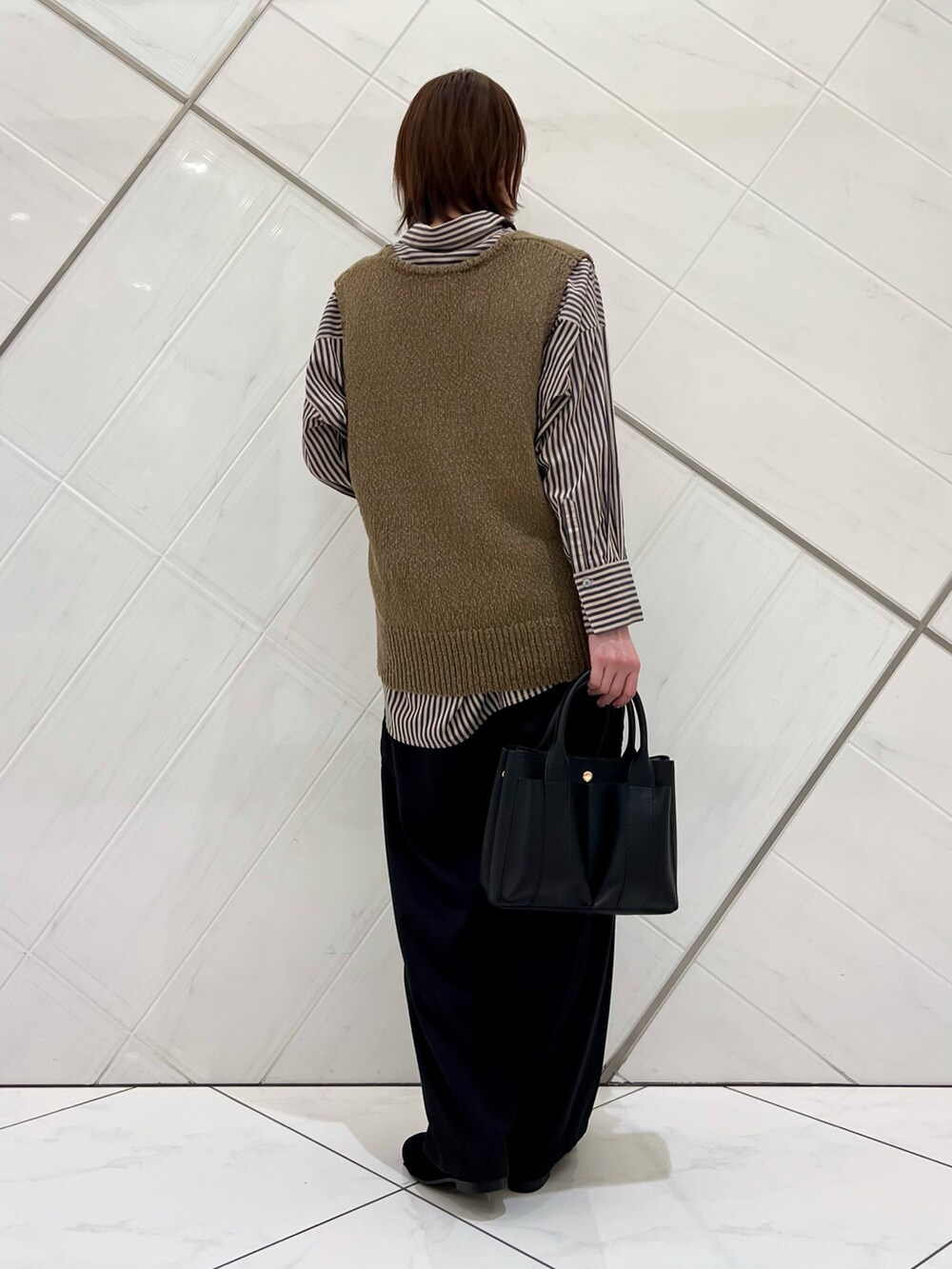 グリーン系のベスト、グレー系のシャツ/ブラウス、ブラック系のその他パンツを着用したレディースの秋コーディネートの3枚目の写真