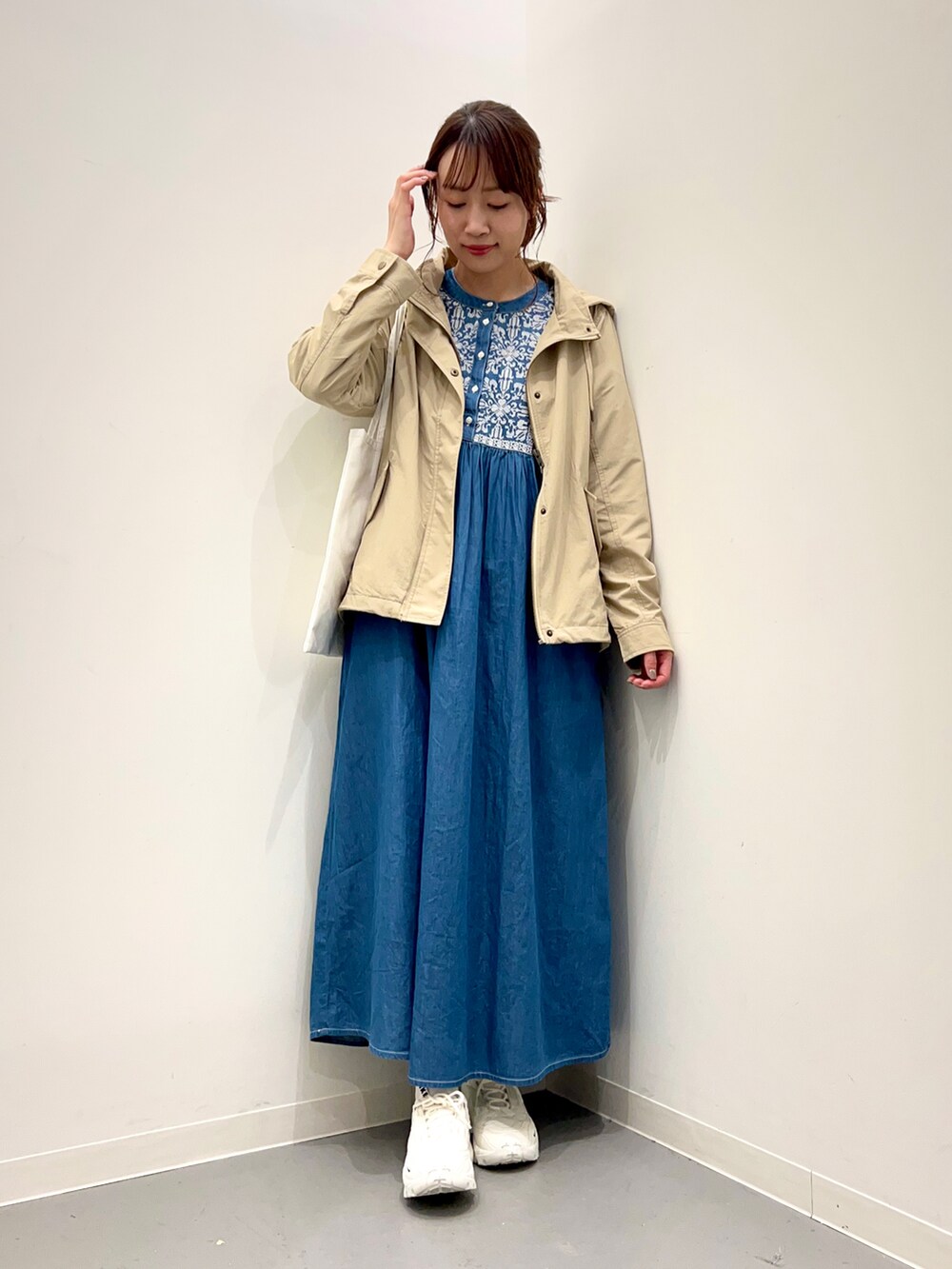 ホワイト系のトートバッグ、ベージュ系のマウンテンパーカー、ブルー系のワンピースを着用したレディースの冬コーディネートの4枚目の写真