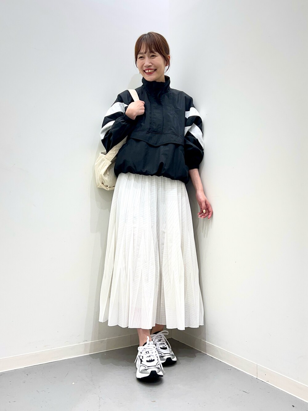 ホワイト系のスニーカー、ホワイト系のスカート、ブラック系のトップスを着用したレディースの春コーディネートの4枚目の写真