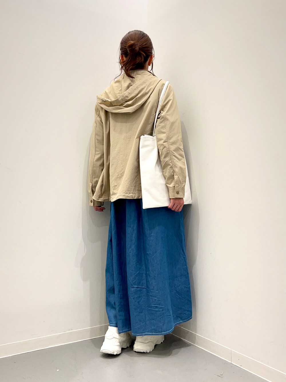 ホワイト系のトートバッグ、ベージュ系のマウンテンパーカー、ブルー系のワンピースを着用したレディースの冬コーディネートの5枚目の写真