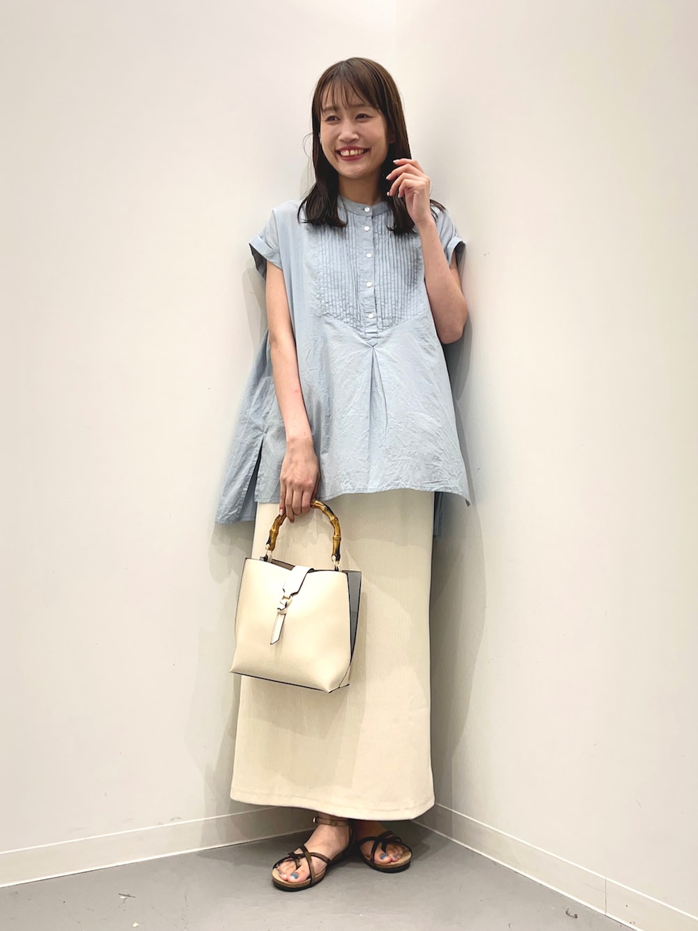 ブルー系のシャツ/ブラウス、ホワイト系のハンドバッグ、ブラウン系のサンダルを着用したレディースの夏コーディネートの4枚目の写真