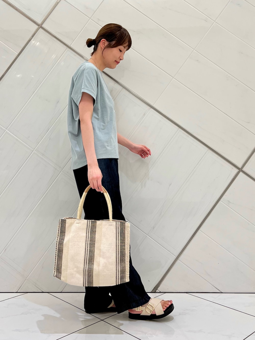 グリーン系のTシャツ/カットソー、ブルー系のデニムパンツ、ホワイト系のトートバッグを着用したレディースの夏コーディネートの2枚目の写真