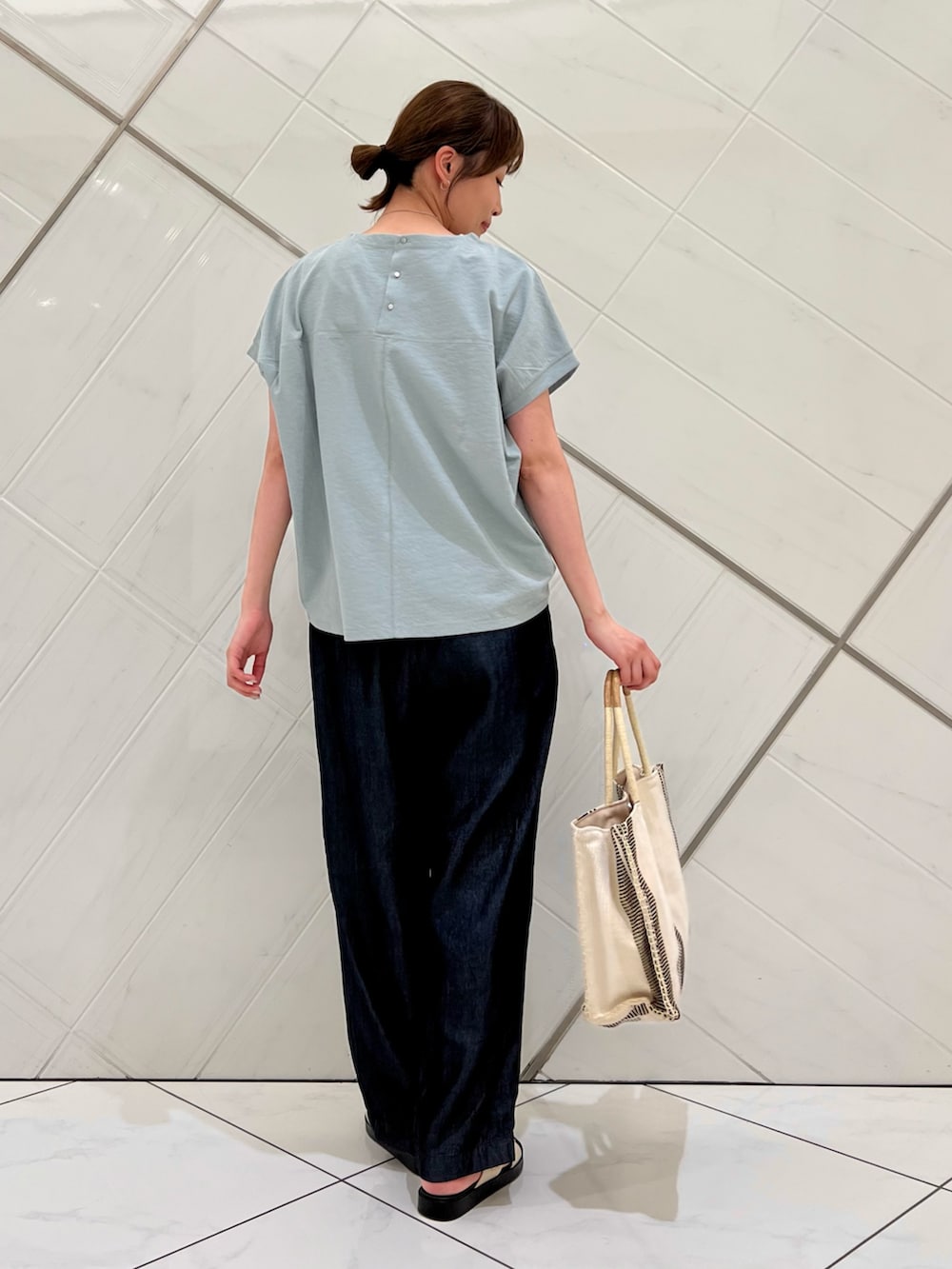 グリーン系のTシャツ/カットソー、ブルー系のデニムパンツ、ホワイト系のトートバッグを着用したレディースの夏コーディネートの3枚目の写真