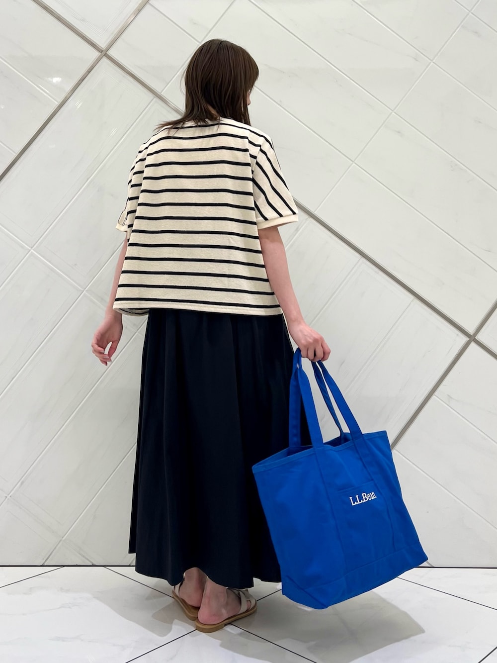 ホワイト系のTシャツ/カットソー、ブラック系のスカート、ブルー系のトートバッグを着用したレディースの夏コーディネートの3枚目の写真