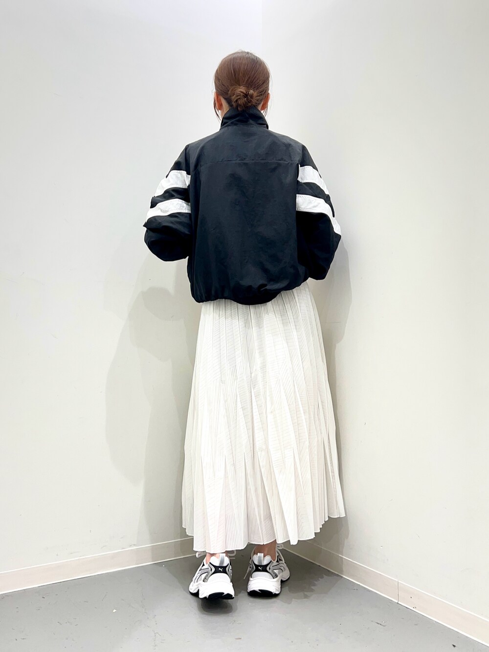 ホワイト系のスニーカー、ホワイト系のスカート、ブラック系のトップスを着用したレディースの春コーディネートの3枚目の写真