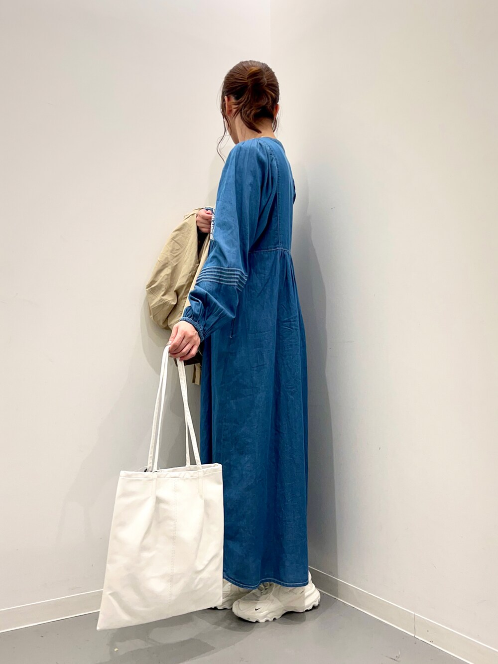 ホワイト系のトートバッグ、ベージュ系のマウンテンパーカー、ブルー系のワンピースを着用したレディースの冬コーディネートの2枚目の写真